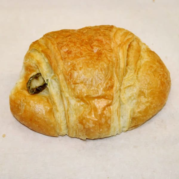 Golden-brown croissant with a visible chocolate filling peeking out from one end.