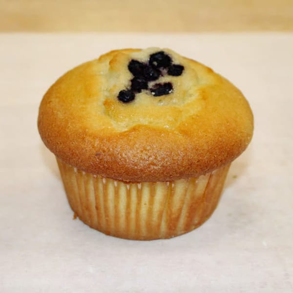A golden-brown blueberry muffin from Dutch Donut Factory, with dark blueberries visible on top.